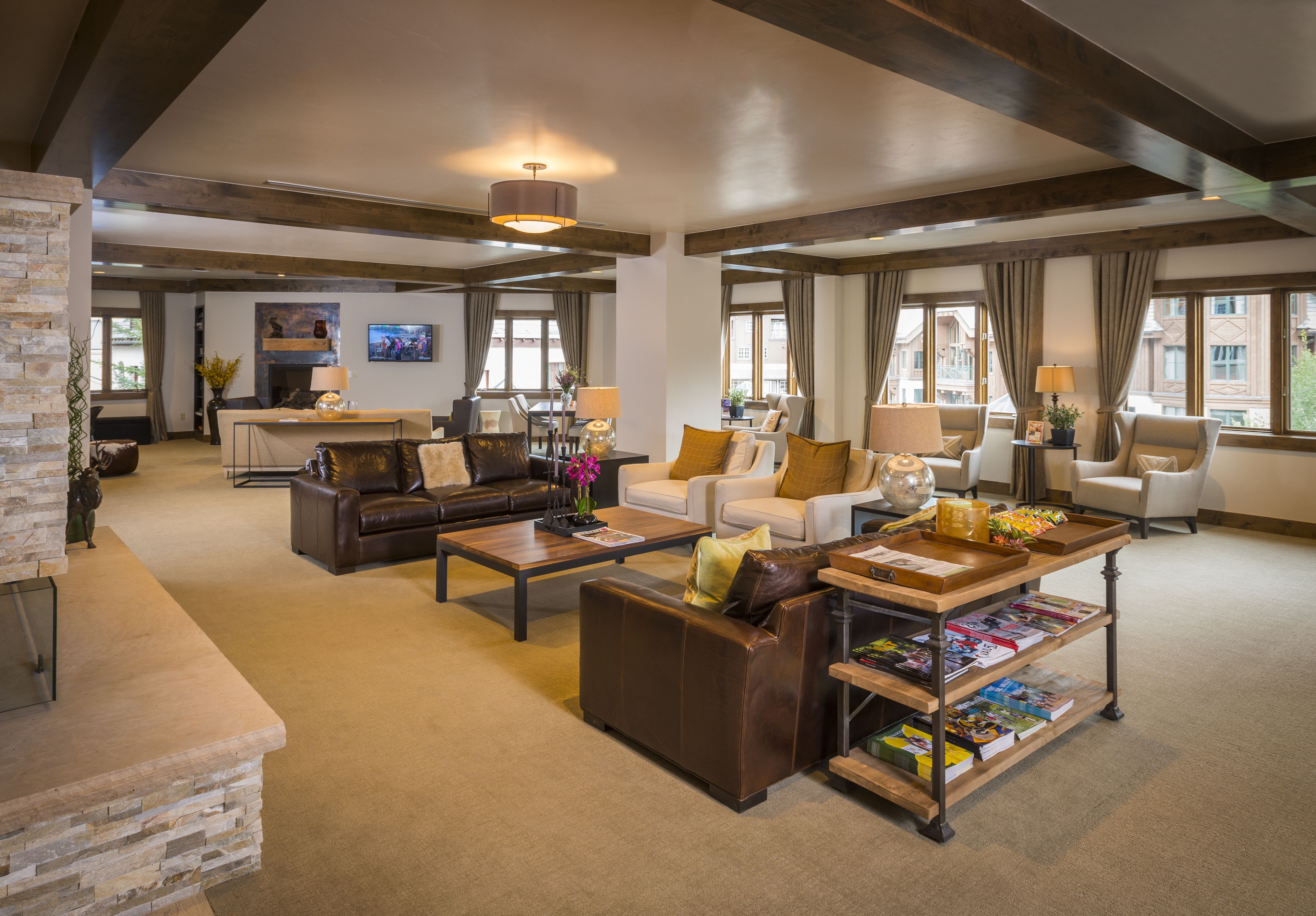 A spacious living room with a fireplace, leather sofas, a coffee table, and a bookshelf.