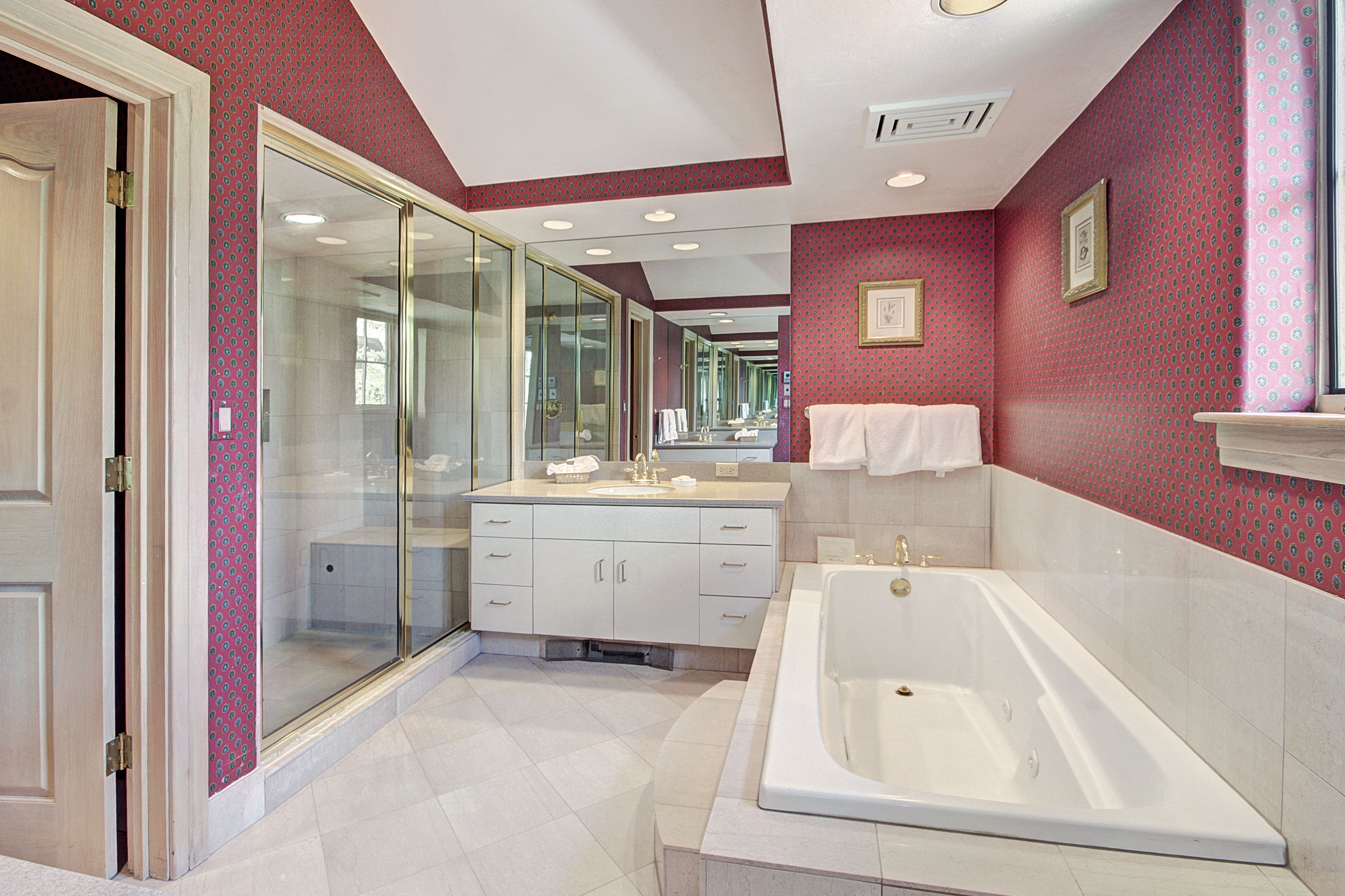 A modern bathroom with a glass shower enclosure, a large bathtub, and a vanity with a mirror.