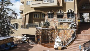 Un hotel de varios pisos con fachada de piedra, balcones y una escalera de piedra que conduce a la entrada.