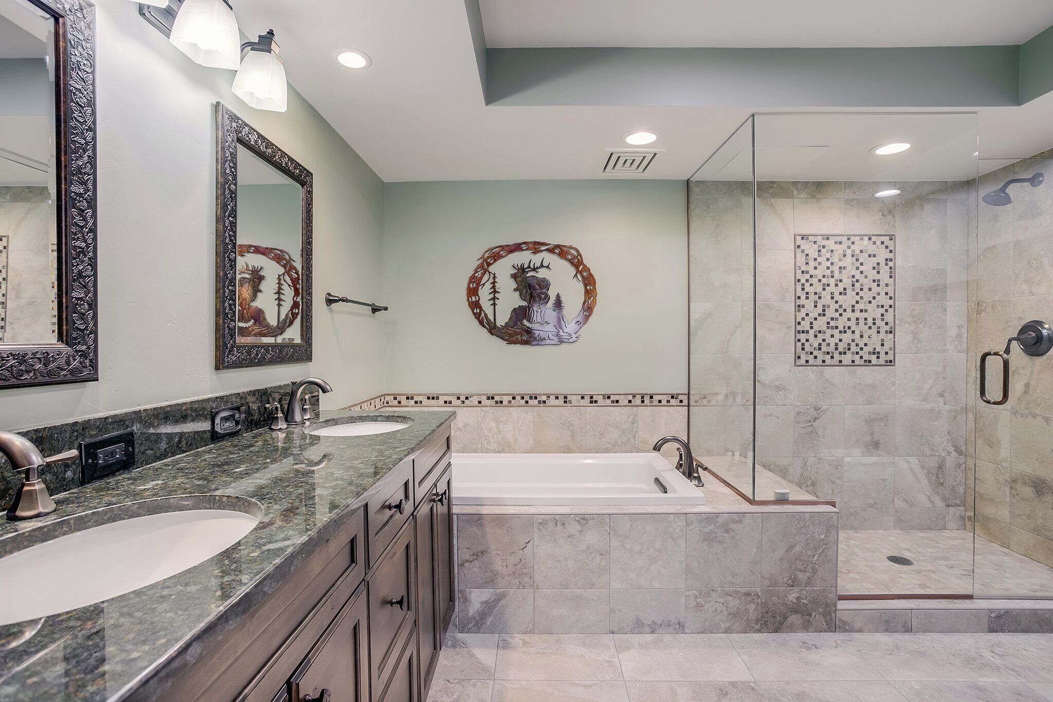 A modern bathroom with a double sink vanity, a large mirror, a freestanding bathtub, and a glass-enclosed shower area.