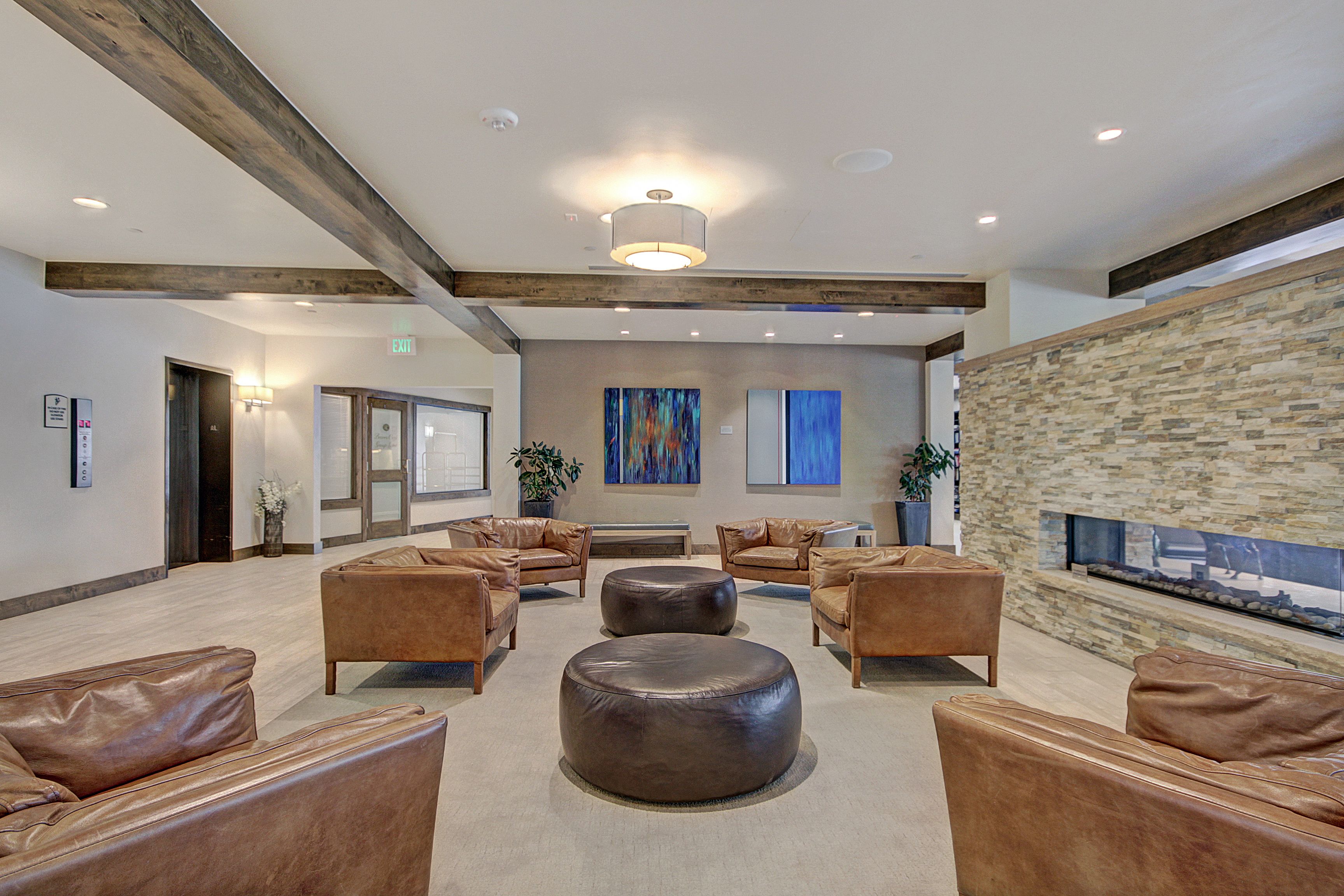 A spacious lobby with leather sofas, a central round ottoman, and a stone accent wall.