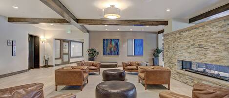 A spacious lobby with leather sofas, a central round ottoman, and a stone accent wall.