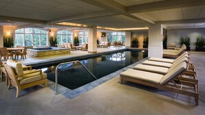 Un área de piscina con sillas de descanso y una mesa de comedor.