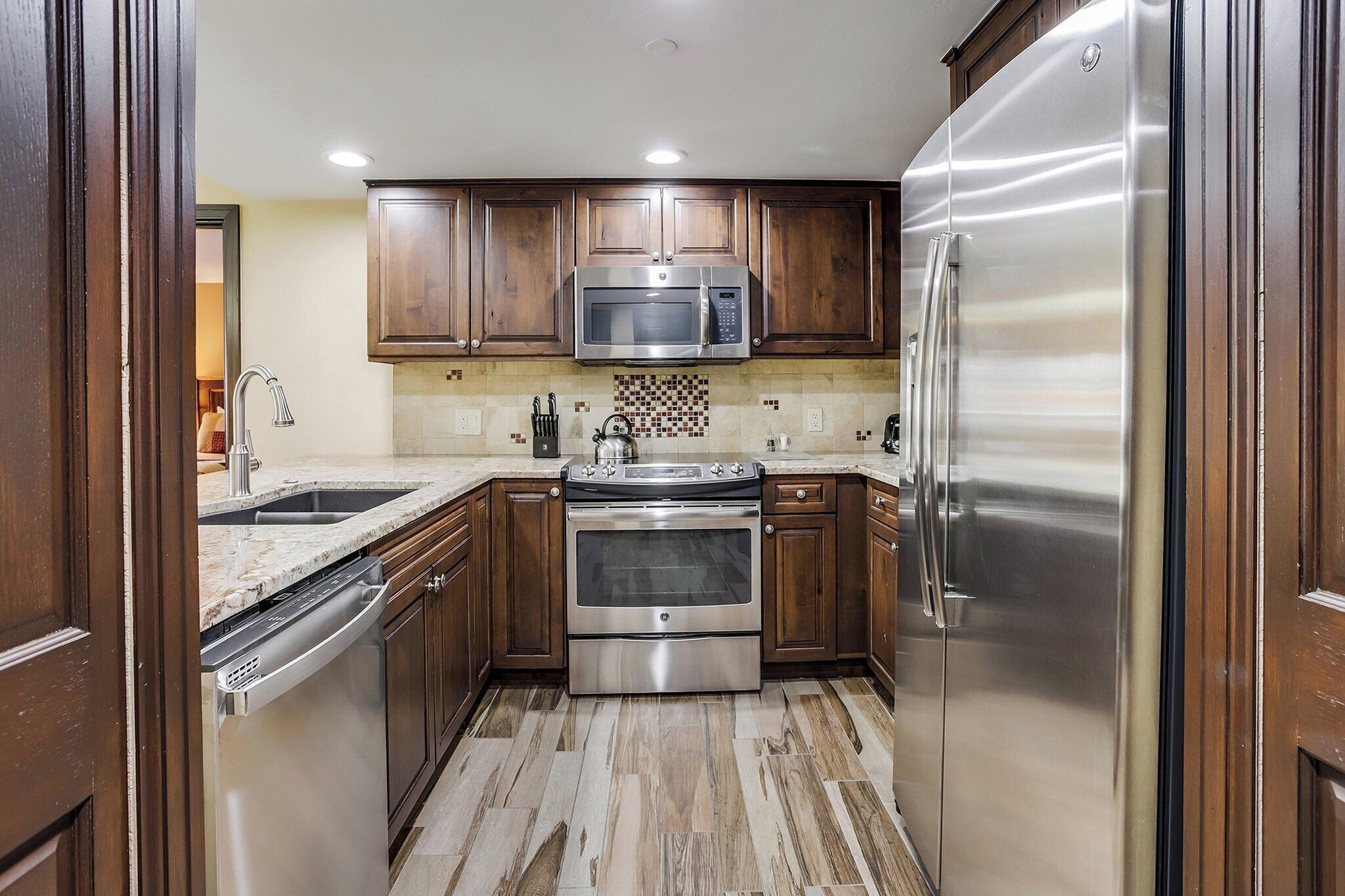 A kitchen with wooden cabinets, a stainless steel refrigerator, a microwave, an oven, and a dishwasher.