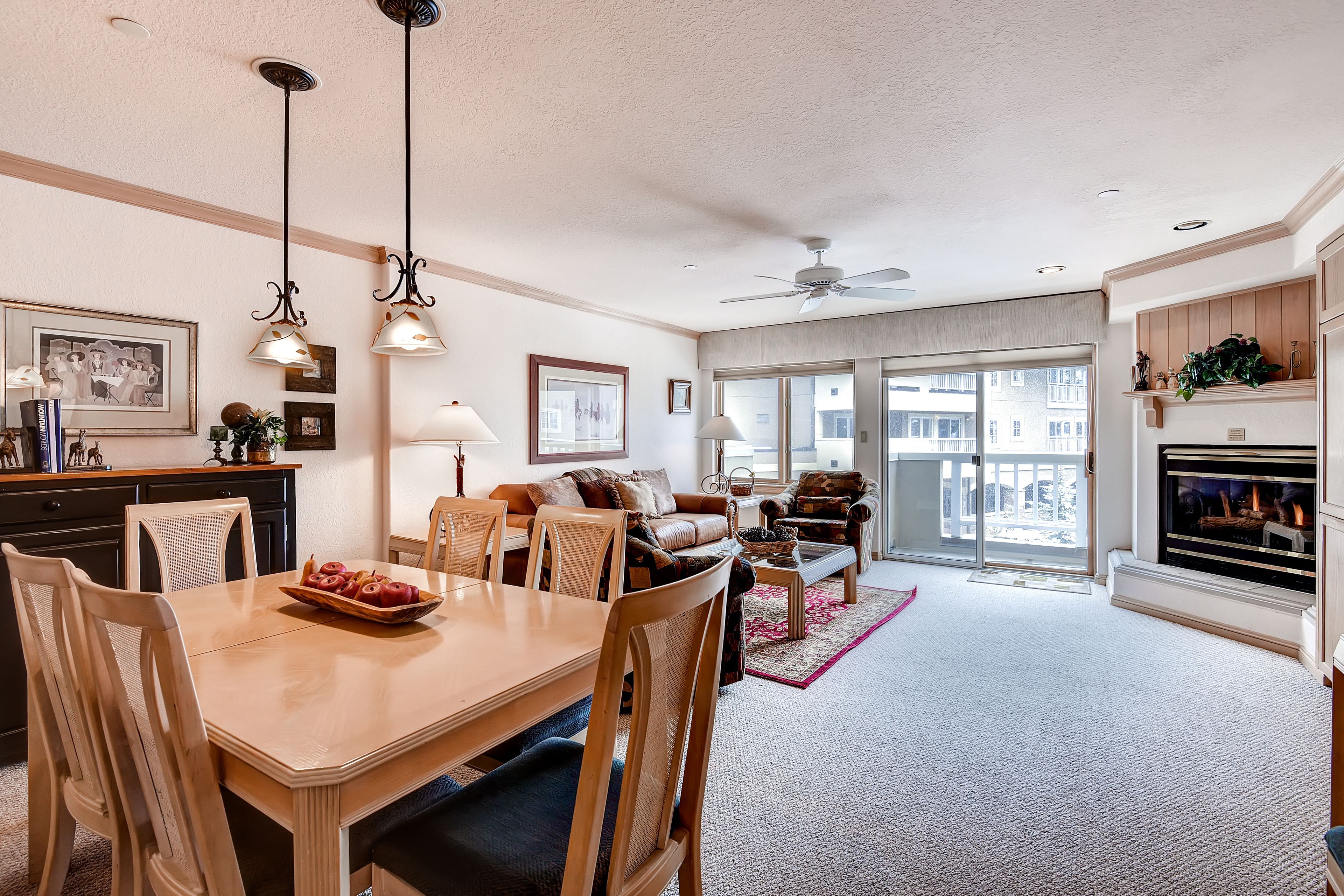 A spacious living room with a dining area, large windows, and a fireplace.