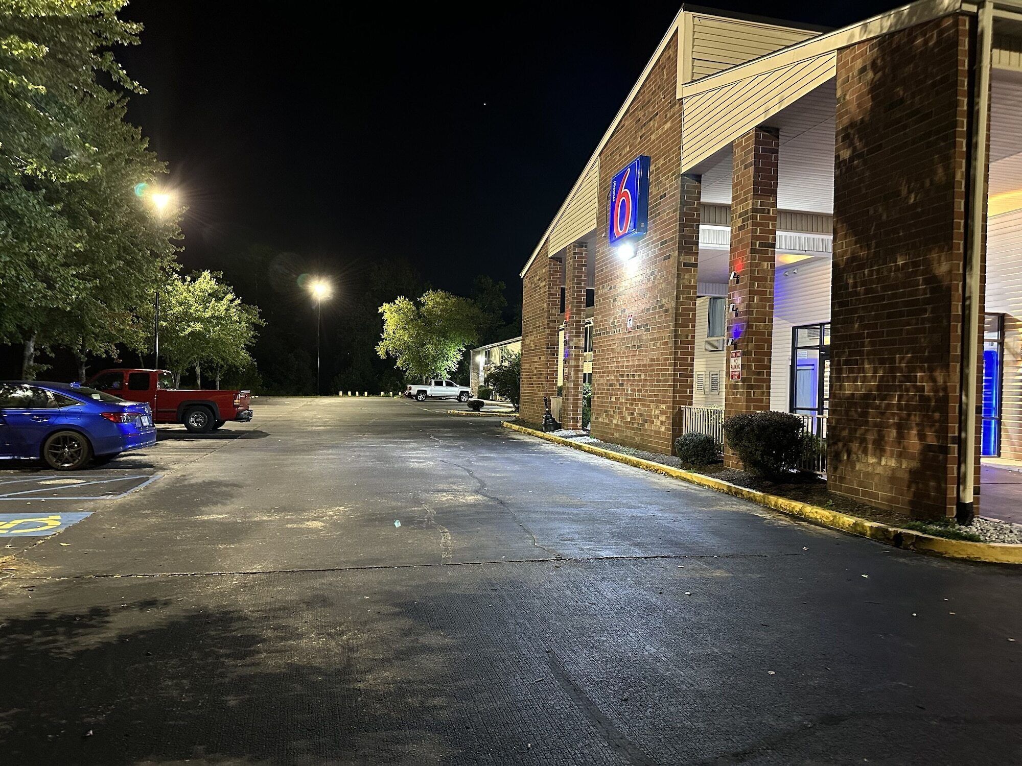 A well-lit motel with a prominent '6' sign, a parking lot, and a red pickup truck parked in front.