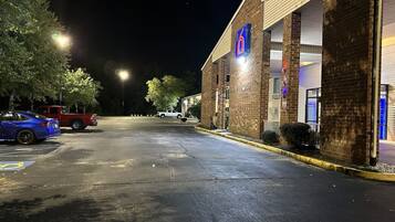 A well-lit motel with a prominent '6' sign, a parking lot, and a red pickup truck parked in front.