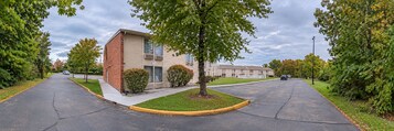 Una calle residencial con una hilera de casas de dos pisos, aceras y árboles.