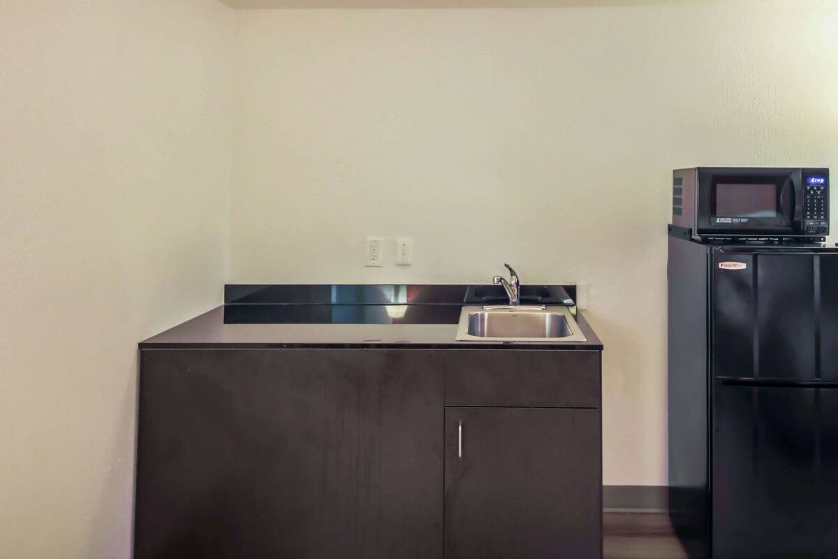 A compact kitchenette with a sink, a microwave, and a refrigerator.