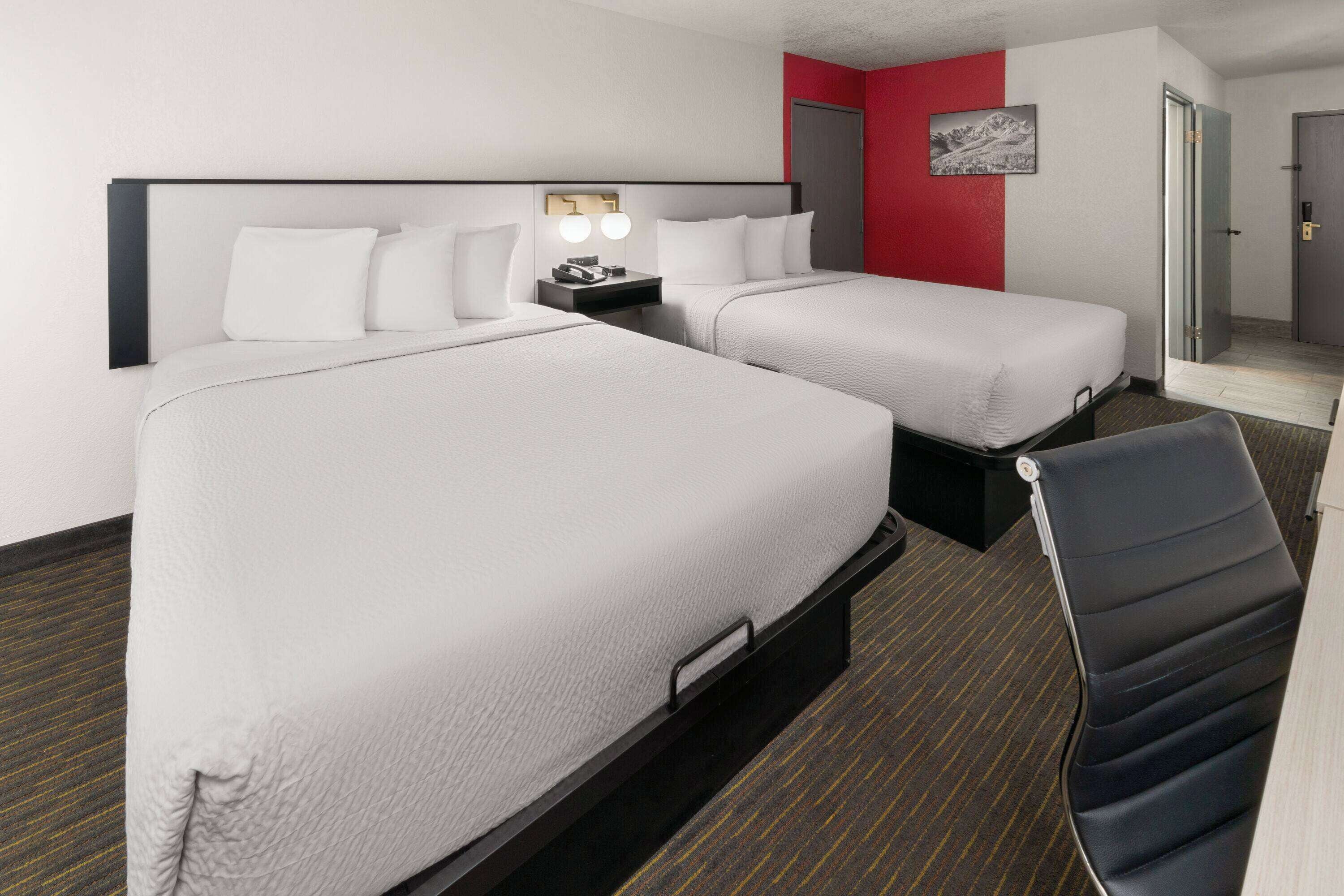 Une chambre d’hôtel avec deux lits, un bureau et une chaise.