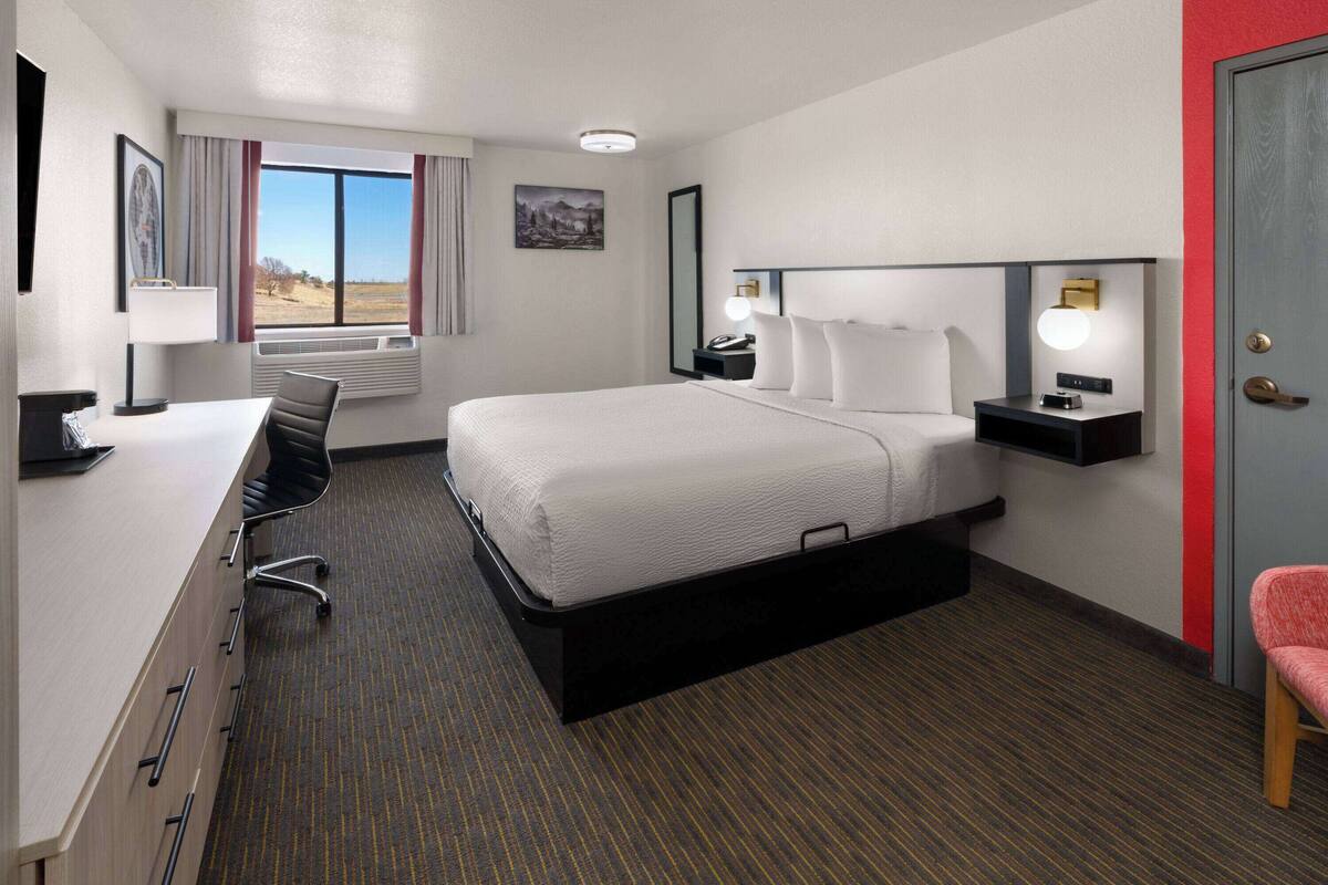Ein Hotelzimmer mit Bett, Schreibtisch, Stuhl und Blick ins Freie.