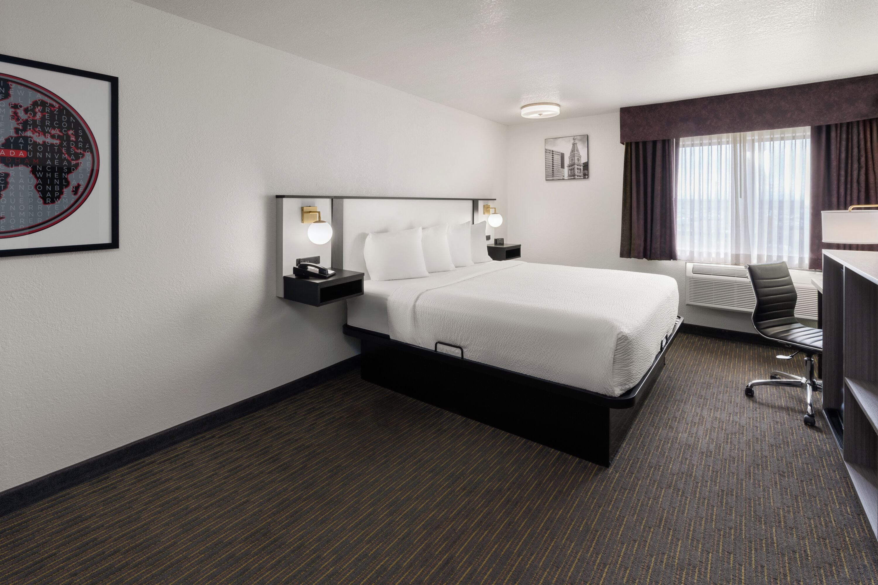 A hotel room with a large bed, bedside tables, a desk, and a chair.