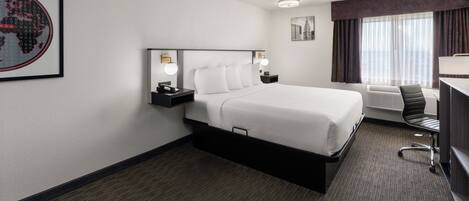 A hotel room with a large bed, bedside tables, a desk, and a chair.