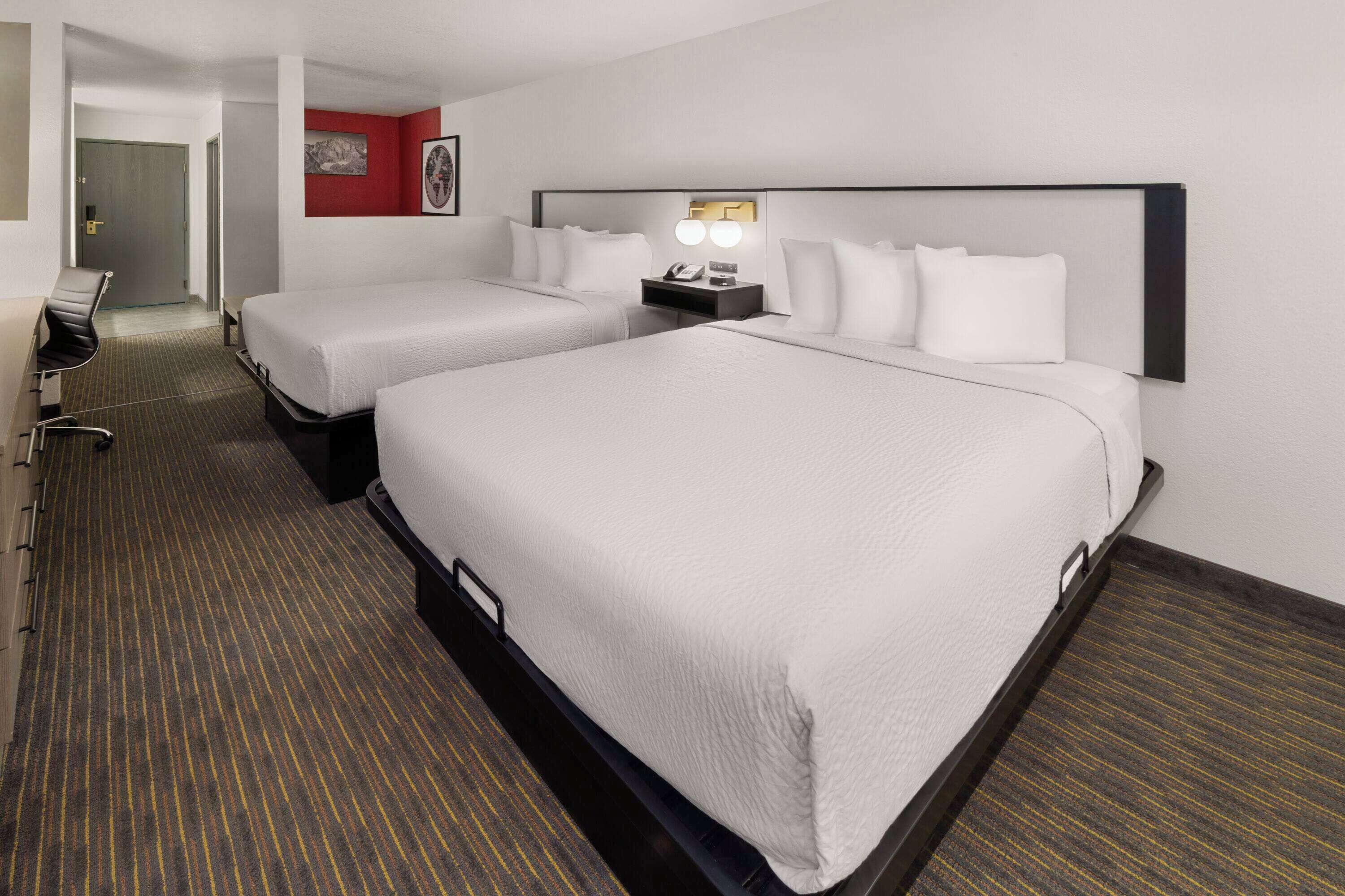 A hotel room with two beds, a desk, and a chair.