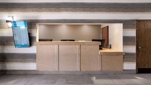 A reception desk with a digital sign, a wooden door, and a tiled floor. - SYLO Hotel Denver Airport, a Ramada by Wyndham (Aurora)