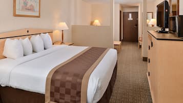A hotel room with a large bed, two bedside lamps, a television, and a desk with a chair.