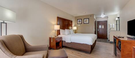 A hotel room with a bed, a sofa, a desk, and a television.
