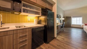 A modern kitchen with wooden cabinets, a black refrigerator, and a yellow-tiled backsplash.