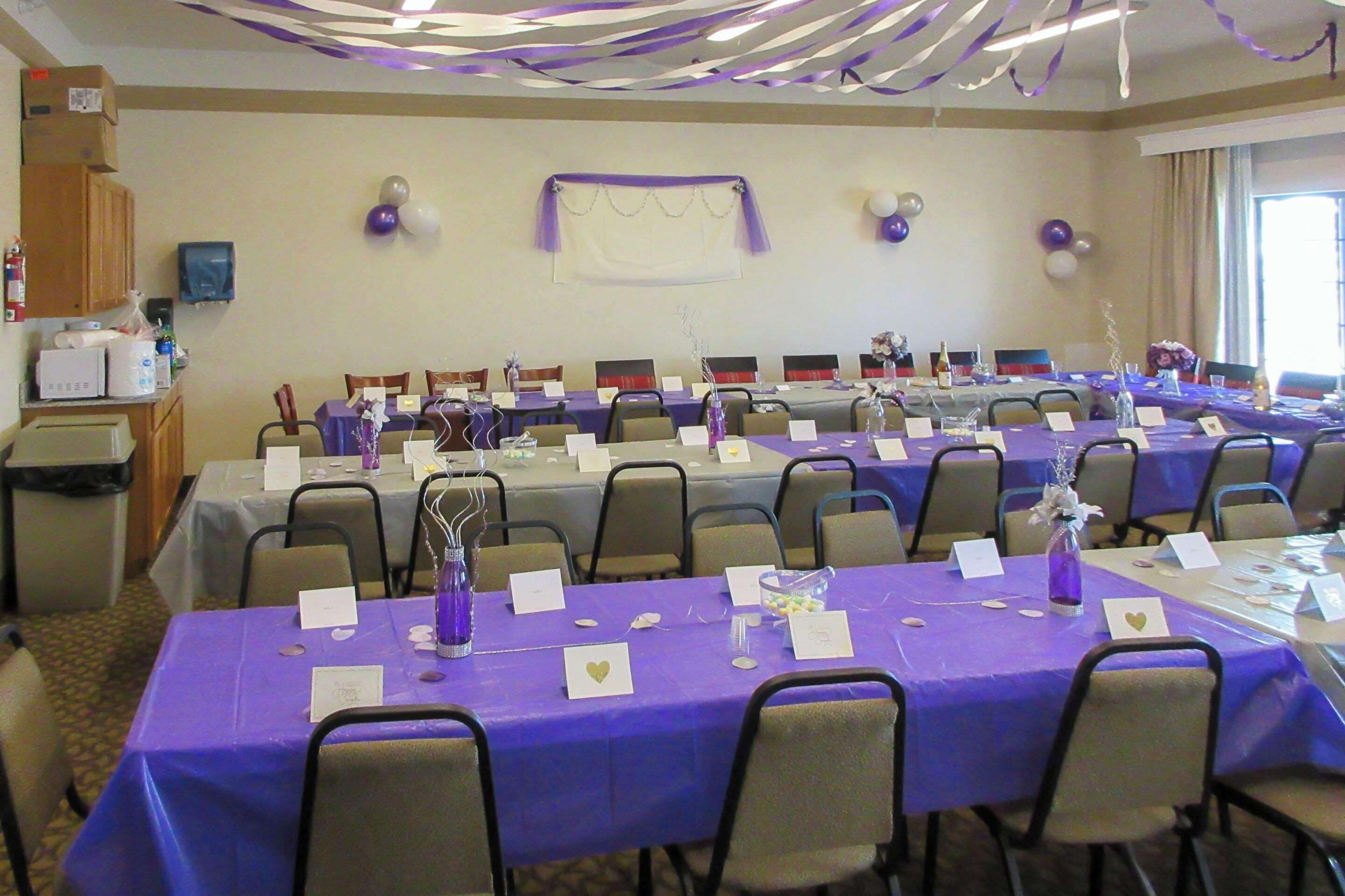 A conference room with tables set for a meeting, featuring name cards and a purple tablecloth.