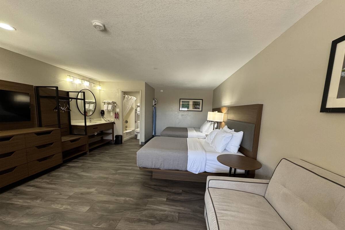 Ein Hotelzimmer mit Bett, Sofa, Fernseher, Bad und Schreibtisch.