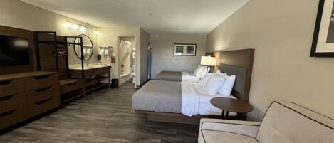 Una habitación de hotel con cama, sofá, televisión, baño y escritorio.