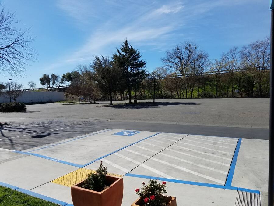 A parking lot with marked handicapped spaces, a pedestrian crossing, and a building in the background.