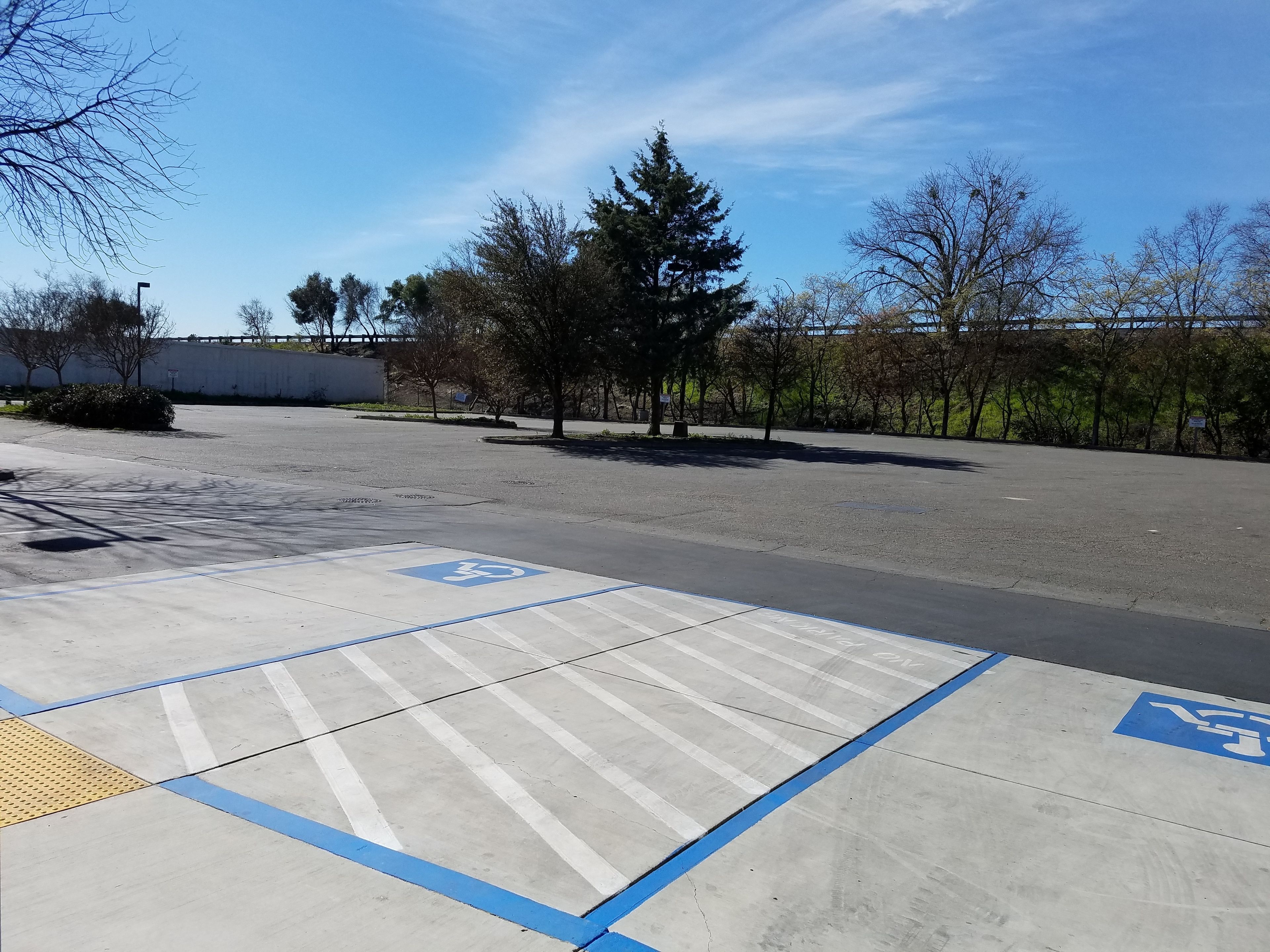 Un estacionamiento con plazas reservadas para personas con discapacidad y cielo despejado.
