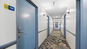 A hotel hallway with blue doors, a carpeted floor, and a sign indicating room number 108. - Days Inn by Wyndham Woodland (Woodland)