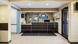 A reception area with a reception desk, a sign for Days Inn, a door, and a potted plant. - Days Inn by Wyndham Woodland (Woodland)