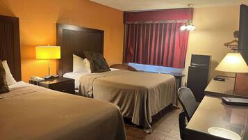 A hotel room with two beds, a desk, a chair, a telephone, a microwave, and a television.