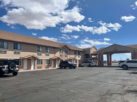 Un motel con varias habitaciones, una estación de servicio y vehículos estacionados.
