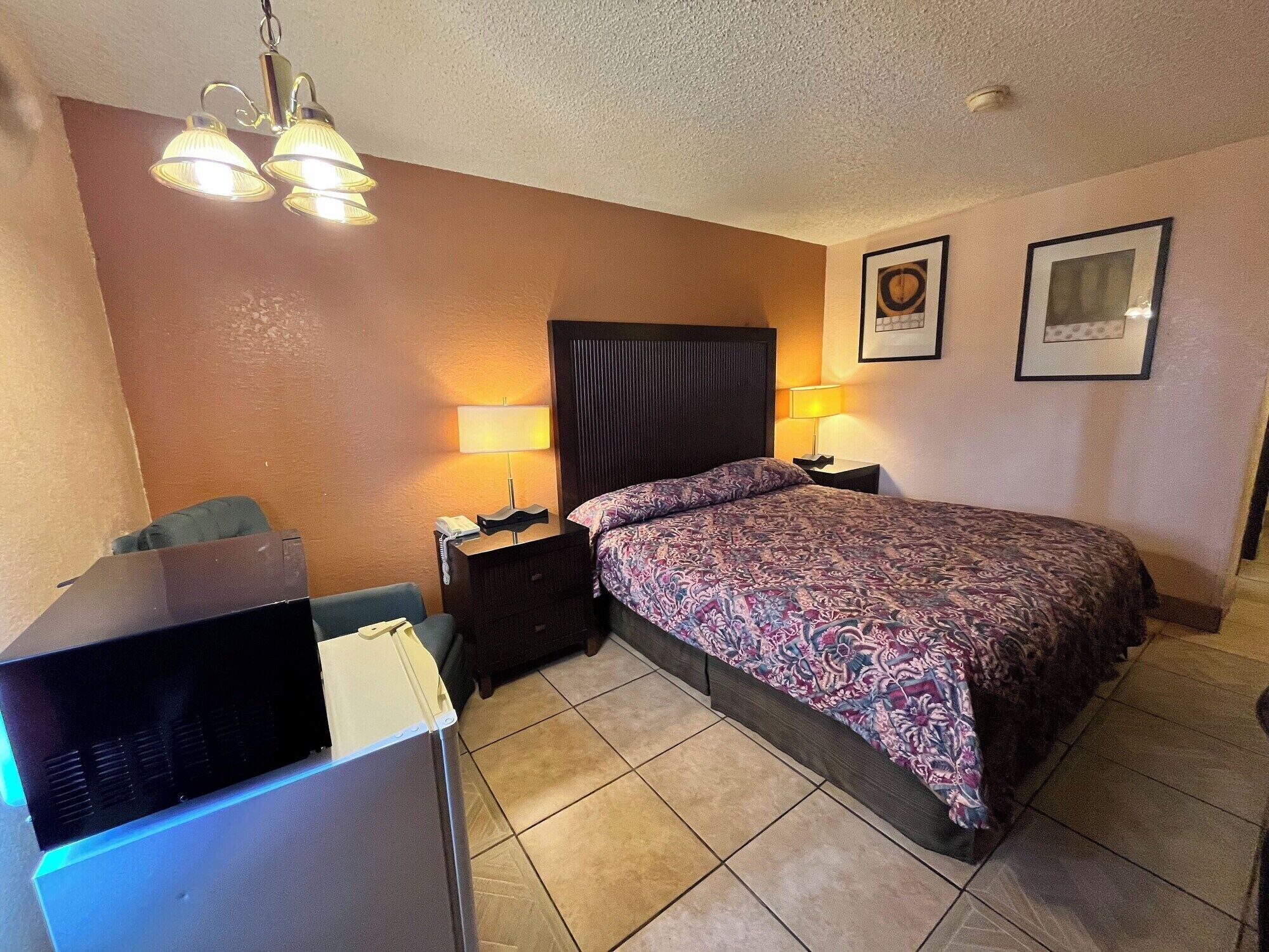 Ein Hotelzimmer mit einem Bett, zwei Nachttischlampen, einem Schreibtisch mit Computer und einem Sessel.