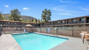 A swimming pool with a fenced area, lounge chairs, and a mountain backdrop.