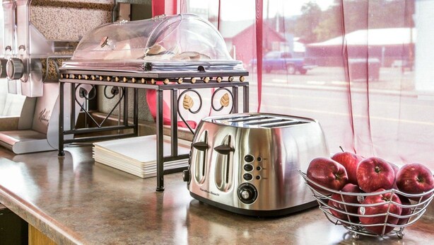 A kitchen counter with a toaster, a bowl of apples, and a cereal container.
