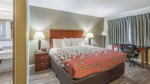 A hotel room with a bed, two bedside lamps, a desk with a chair, and a window with curtains.