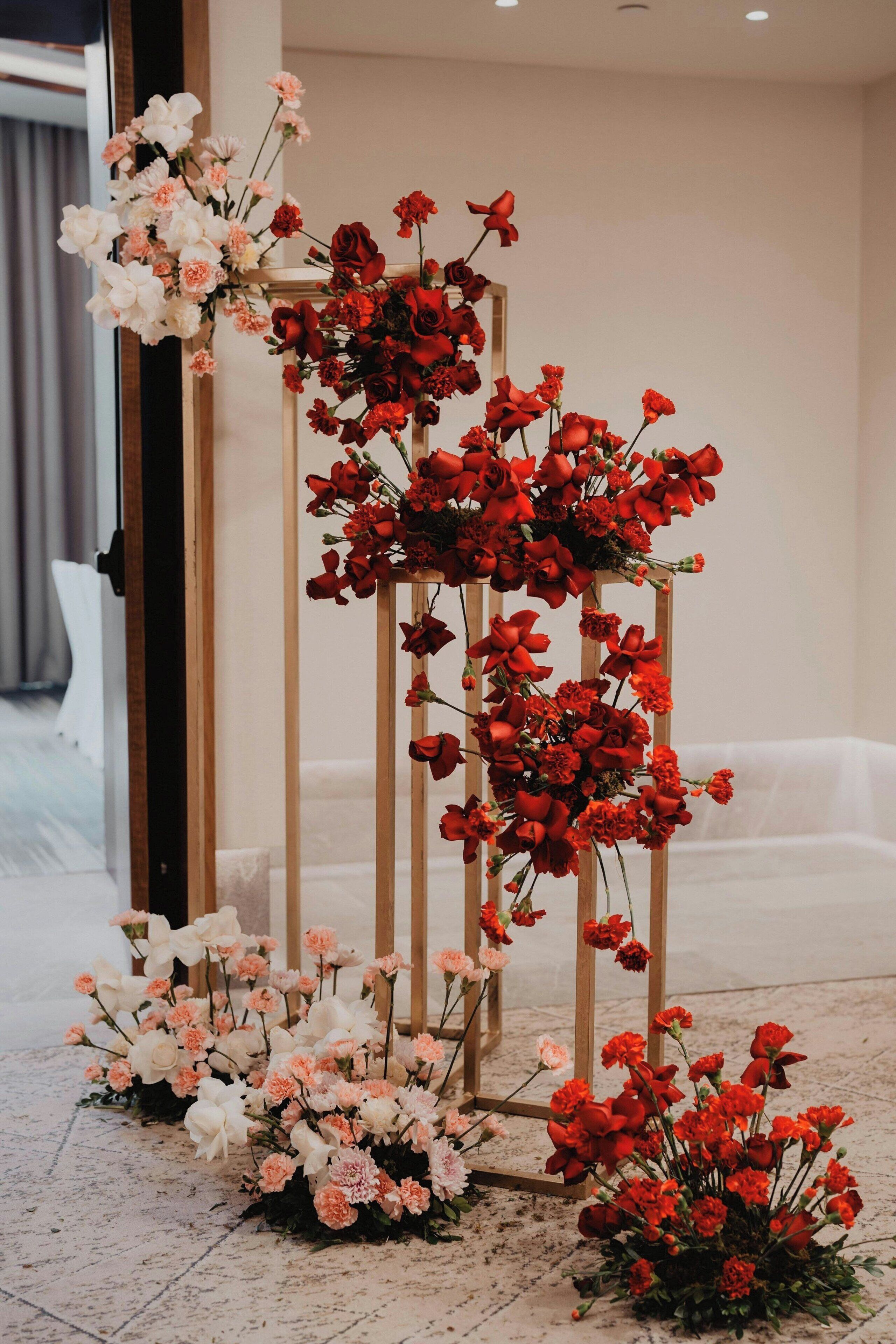 Un arreglo floral con rosas y clavelinas sobre un soporte de madera.