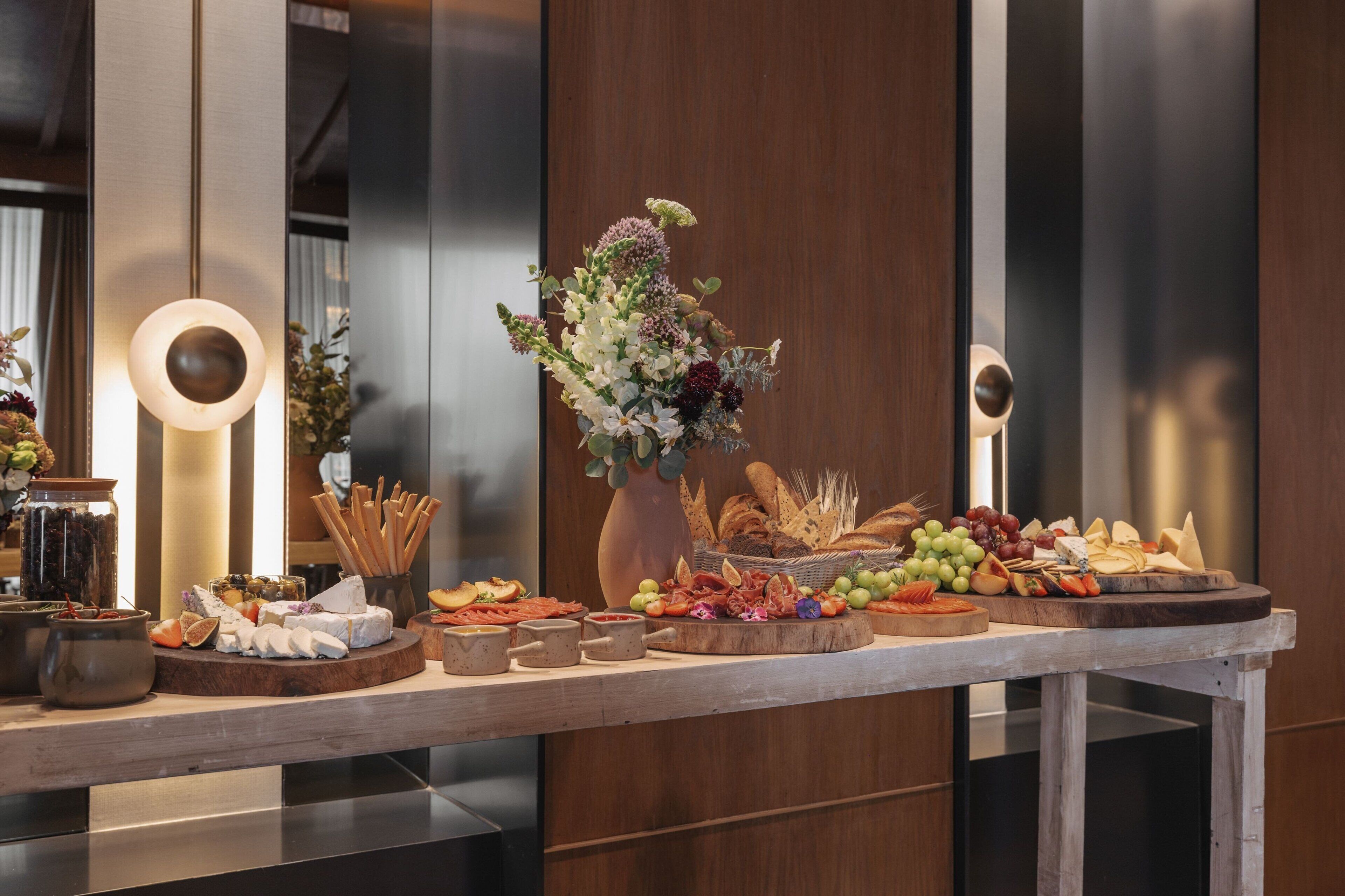 A buffet table with various cheeses, fruits, and breads.