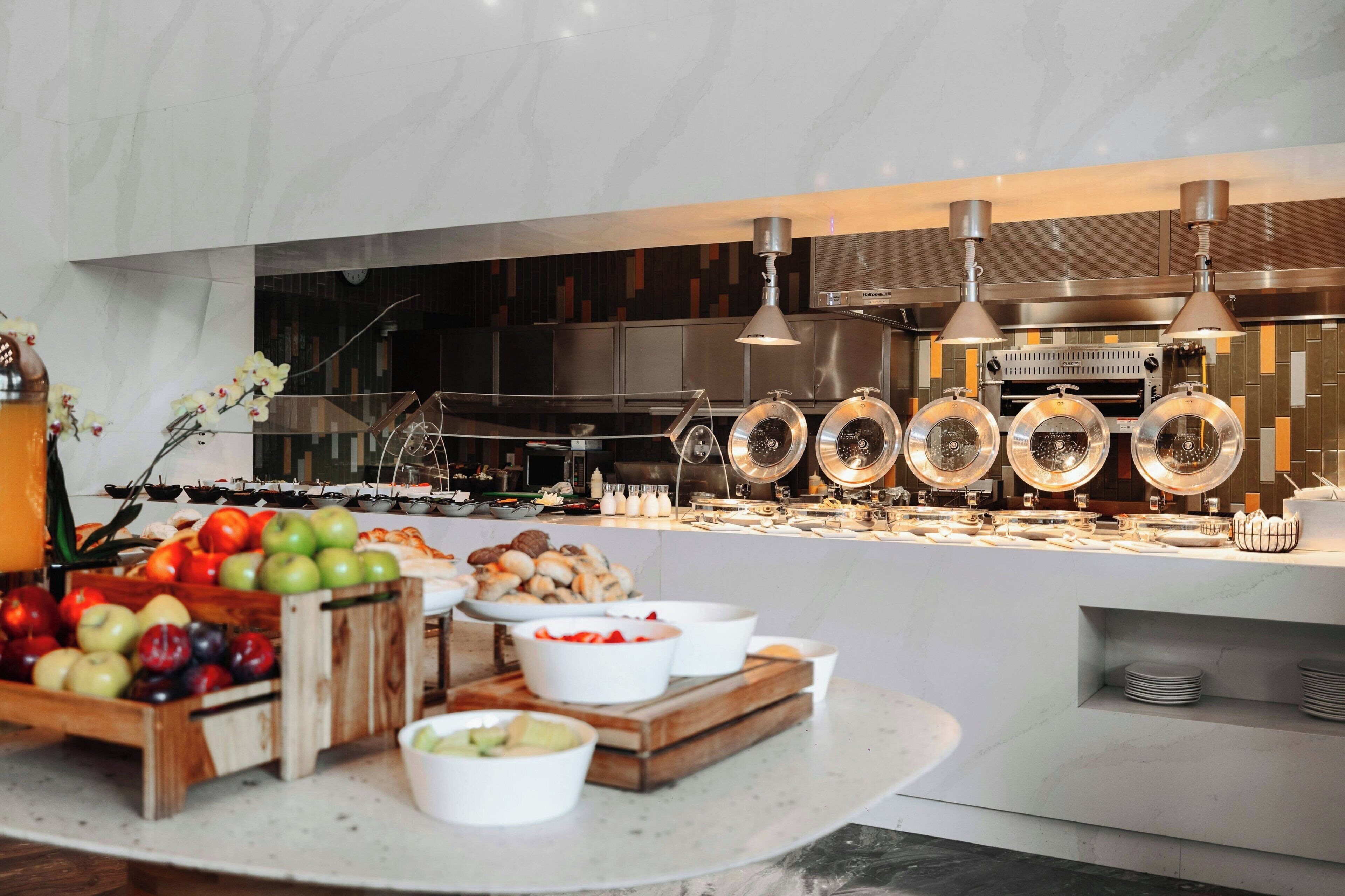 Un aparador tipus buffet amb diversos plats i una cuina moderna al fons.