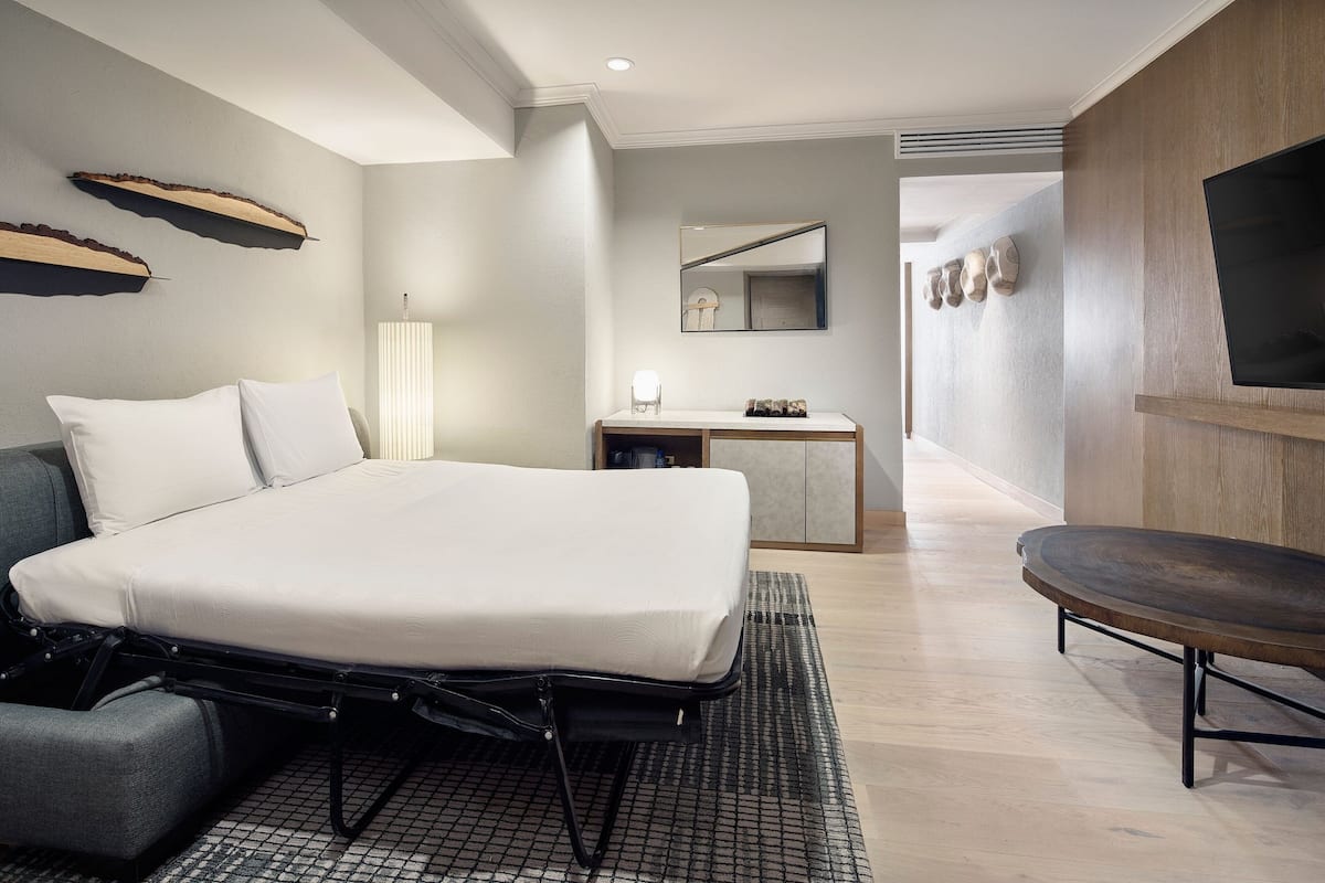Een moderne hotelkamer met een bed, een bureau, een televisie en een zithoek.
