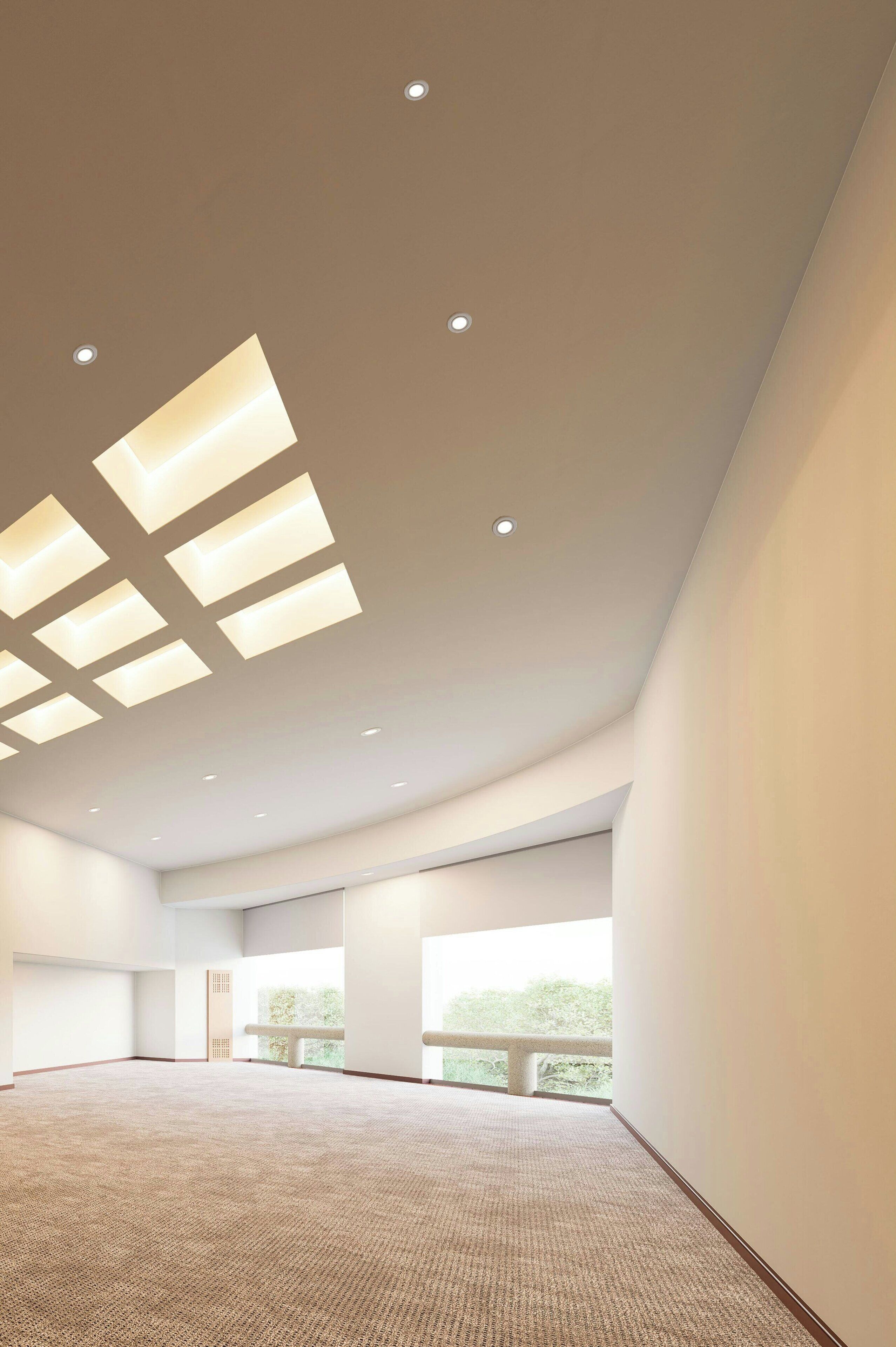 Une pièce spacieuse avec un plafond haut, des luminaires encastrés et de grandes fenêtres.