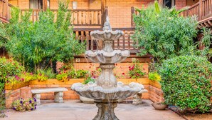 A courtyard with a stone fountain, surrounded by brick walls and wooden balconies. - Clarion Inn Sierra Vista near Ft. Huachuca (Sierra Vista)