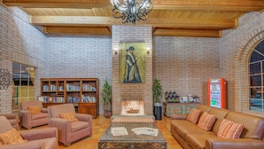 A cozy lounge area with leather sofas, a coffee table, and a fireplace. There are bookshelves and a Coca-Cola refrigerator. - Clarion Inn Sierra Vista near Ft. Huachuca (Sierra Vista)