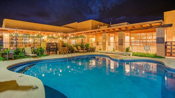 A swimming pool with lounge chairs and a covered patio area at night. - Clarion Inn Sierra Vista near Ft. Huachuca (Sierra Vista)
