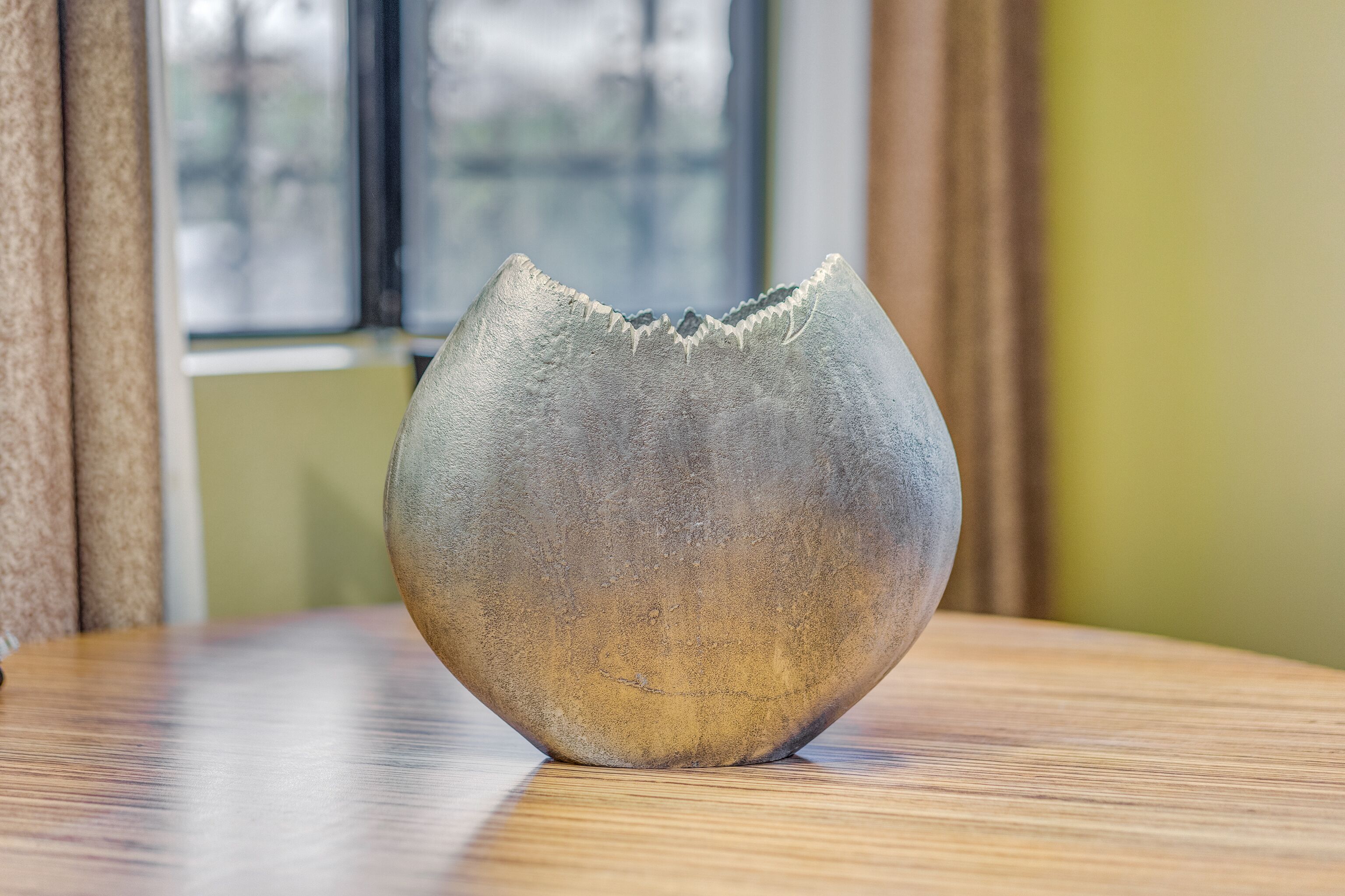 A ceramic bowl on a wooden table with a window in the background.