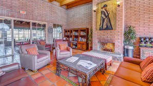 A spacious lobby with brick walls, leather seating, a coffee table, and a bookshelf. - Clarion Inn Sierra Vista near Ft. Huachuca (Sierra Vista)