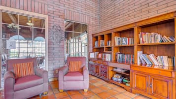 Un coin lecture confortable avec deux fauteuils, une bibliothèque en bois et un mur en briques.