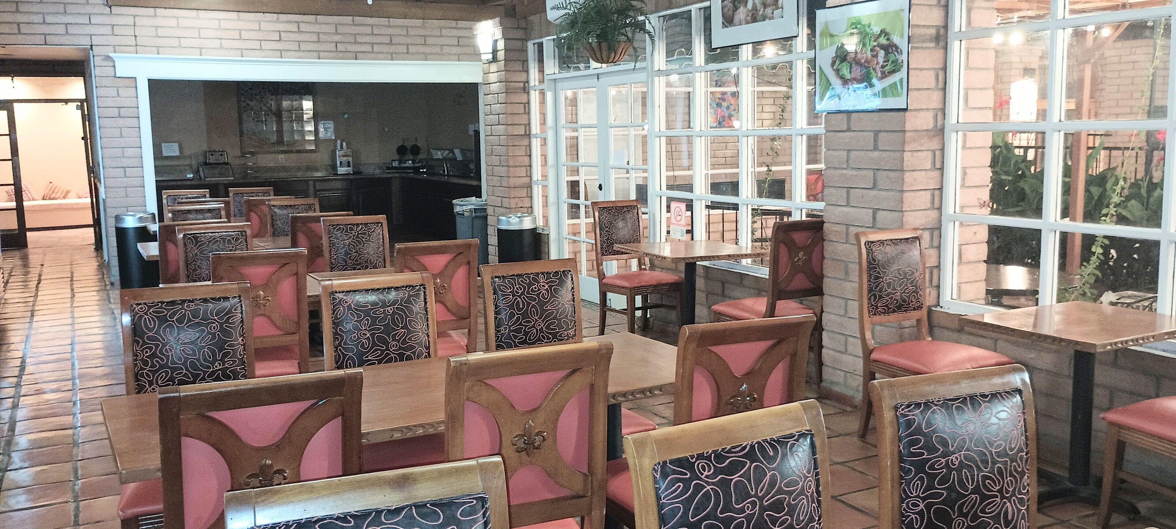 A restaurant with brick walls, wooden tables and chairs, and large windows.