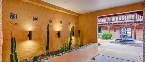 A courtyard with a cactus garden, a fountain, and a building with a balcony.