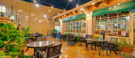 An outdoor patio area with brick walls, string lights, and outdoor seating.