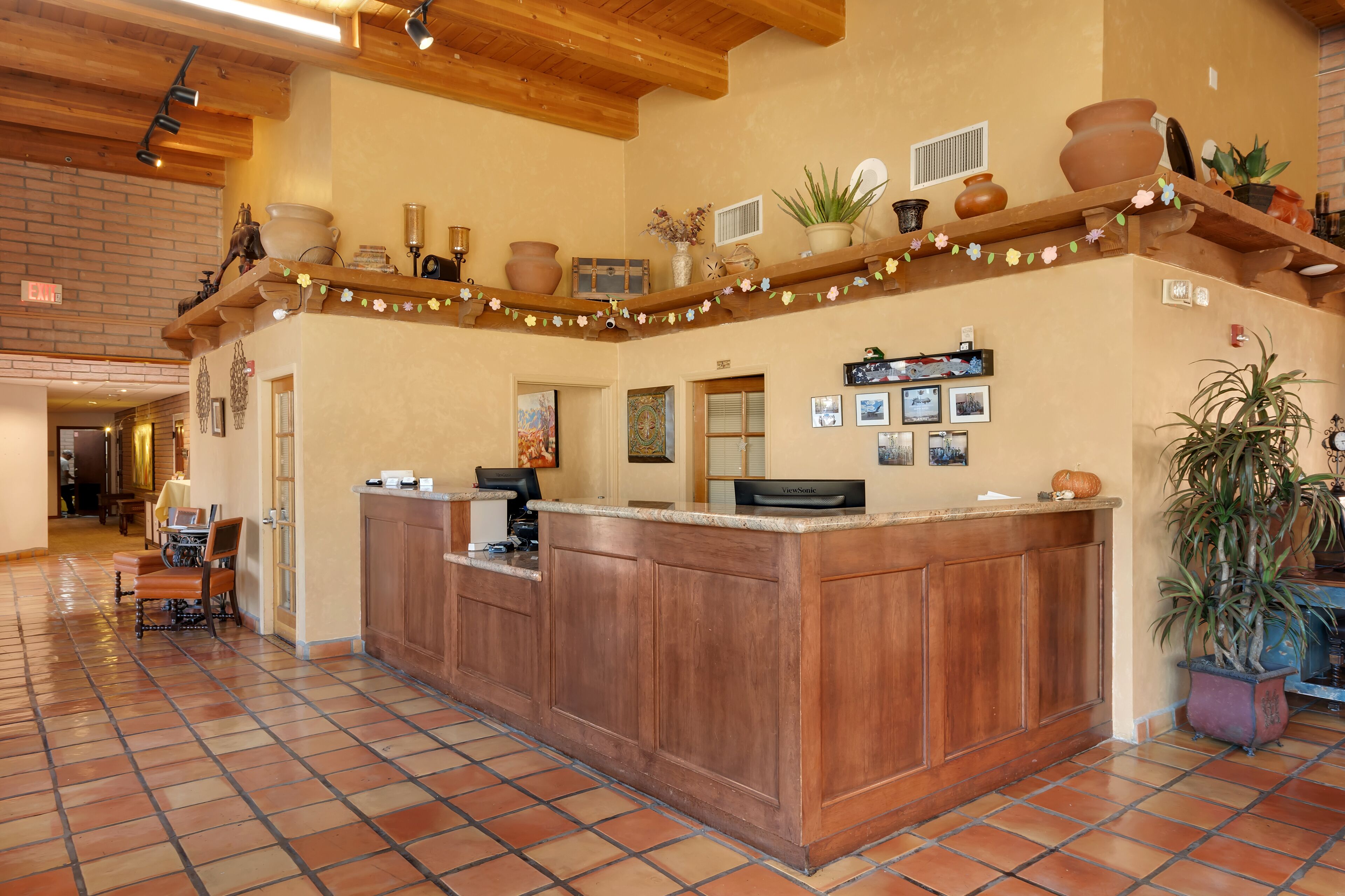 A reception area with a wooden counter, tiled floor, and various decorative items on shelves.